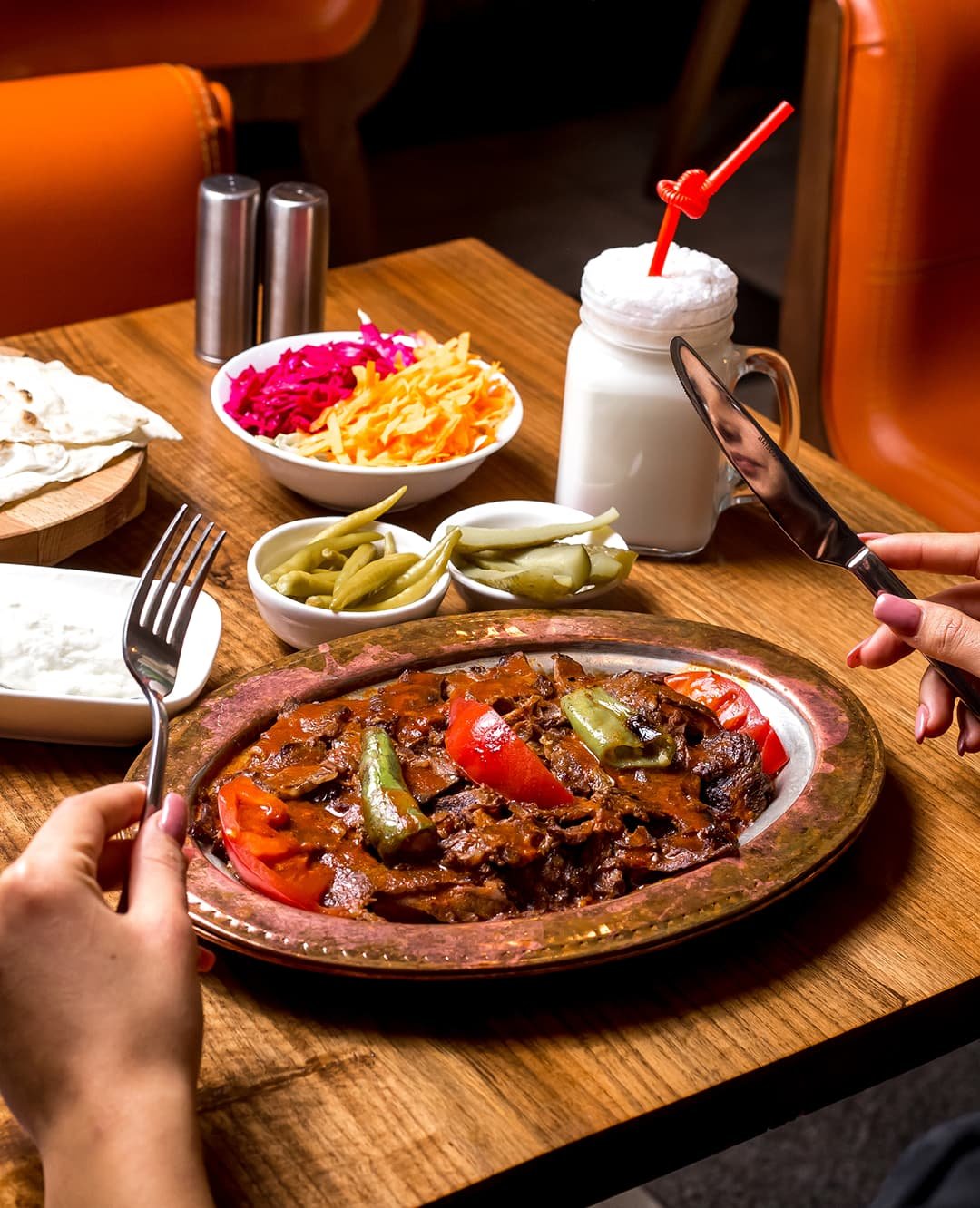 woman-is-served-iskender-kebab-copper-platter-with-pickles-yogurt-ayran 1